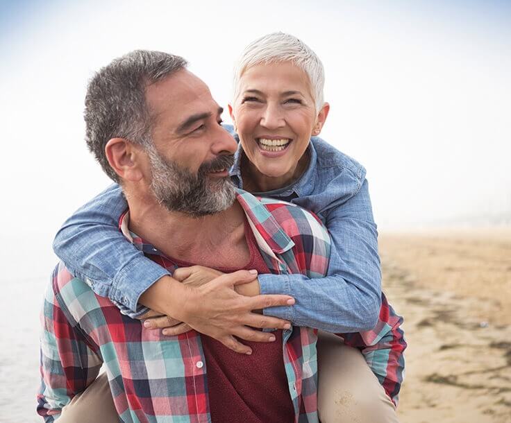 happy senior couple walking on the beach together