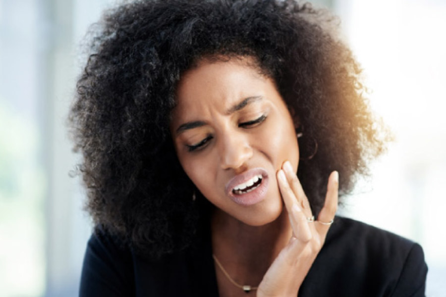 woman holds her jaw in pain with a toothache