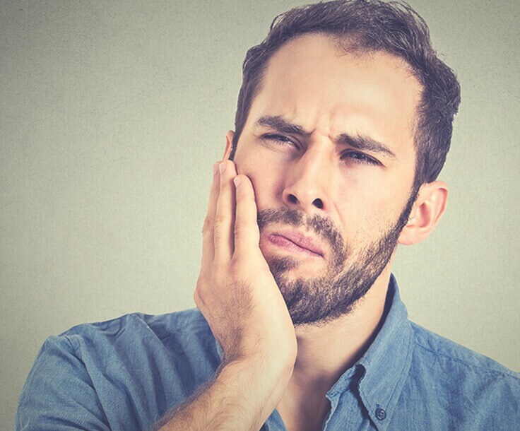 man holding his jaw in pain