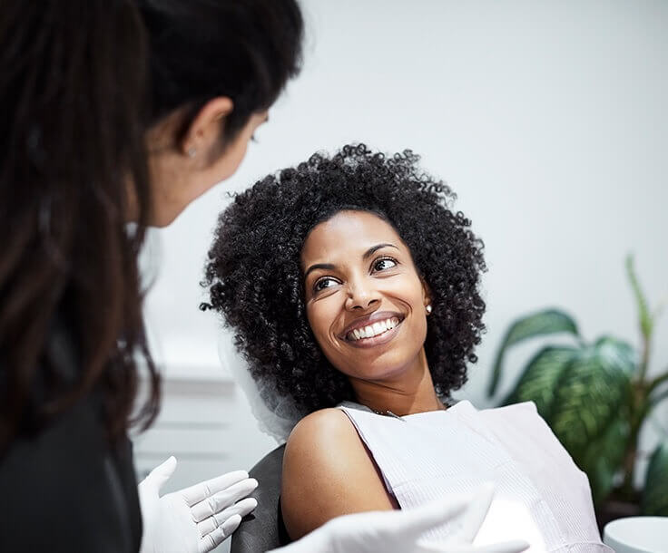 woman with a beautiful, white smile speaking with her dentist