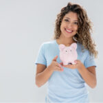 woman holds a piggybank and smiles after learning about affordable dentistry