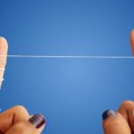 should you floss before or after brushing, fingers holding floss
