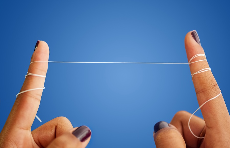 should you floss before or after brushing, fingers holding floss